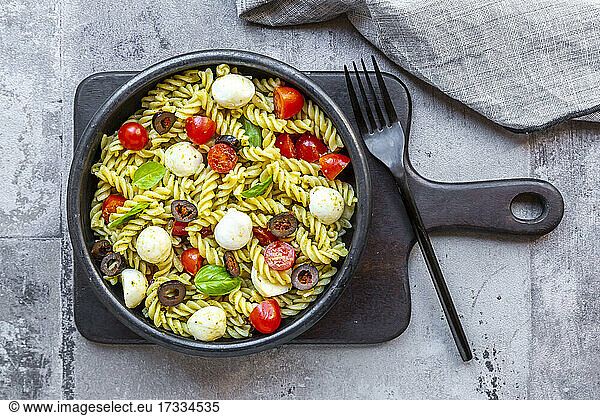 Bowl of ready-to-eat pasta salad with cherry tomatoes  olives  mozzarella cheese and basil