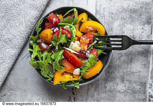 Bowl of salad with red and yellow tomatoes arugula and Parmesan