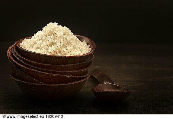Bowl of sea salt on wooden table  close up
