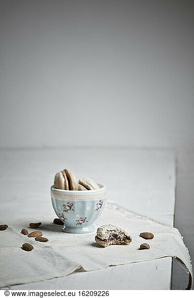 Bowl with macaroons while almonds scattered
