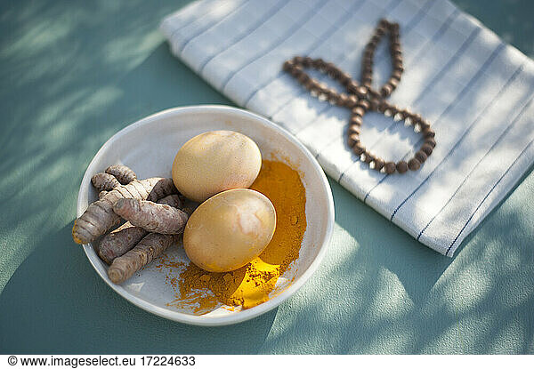 Bowl with turmeric roots turmeric powder and unpainted Easter eggs