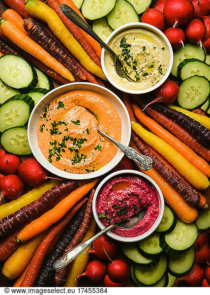 Bowls of different flavoured hummus and raw vegetables for dipping.