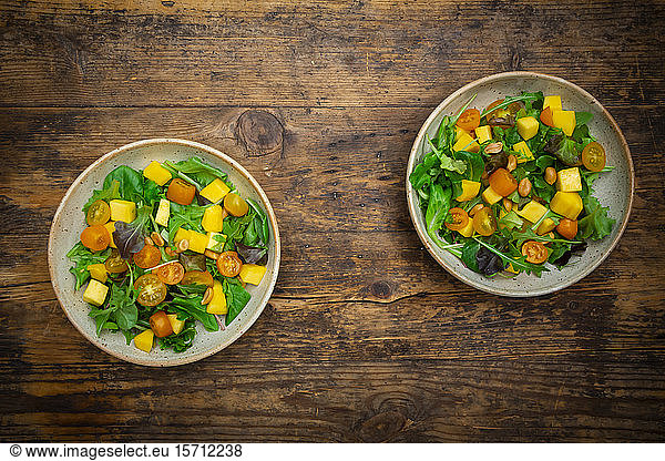 Bowls of salad with spinach  mango fruit  arugula and roasted peanuts
