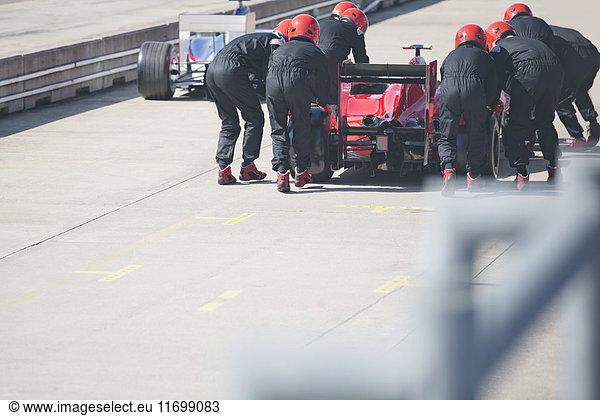 Boxencrew schiebt Formel-1-Rennwagen aus der Boxengasse