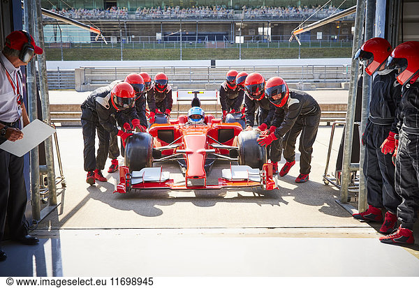 Boxencrew schiebt Formel-1-Rennwagen in die Reparaturwerkstatt