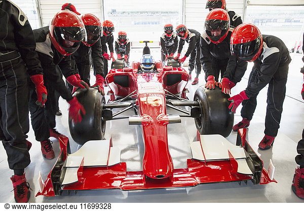 Boxencrew schiebt Formel-1-Rennwagen in die Reparaturwerkstatt