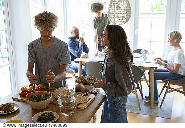 Boy and girl preparing dinner for family in background at home