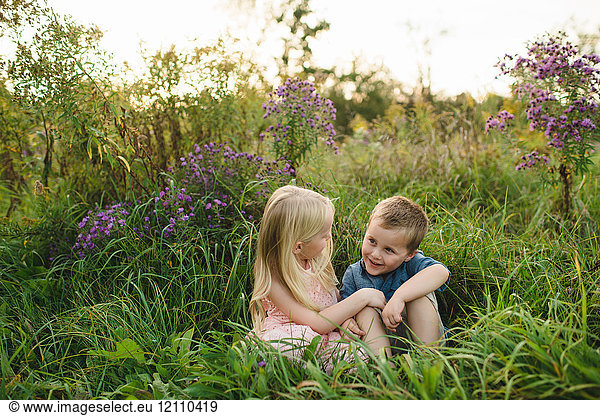Boy and girl sitting in tall grass together