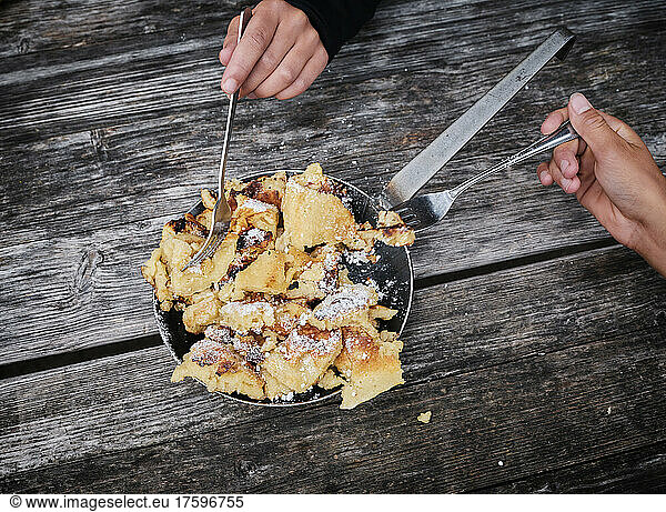 Boy and girl with fork taking Kaiserschmarrn on wooden table