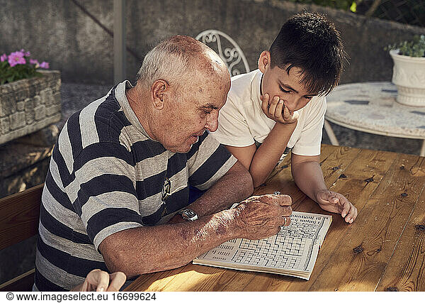 Boy and his grandfather making crosswords