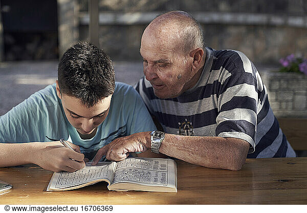 Boy and his grandfather making crosswords
