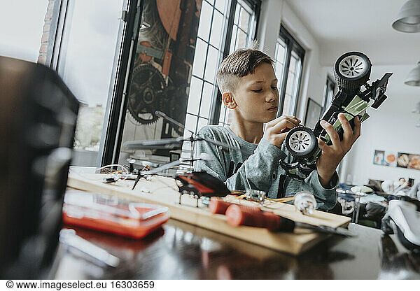 Boy assembling on remote-controlled toy car with screwdriver