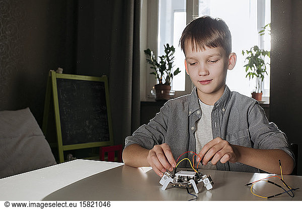 Boy assembling robot at home