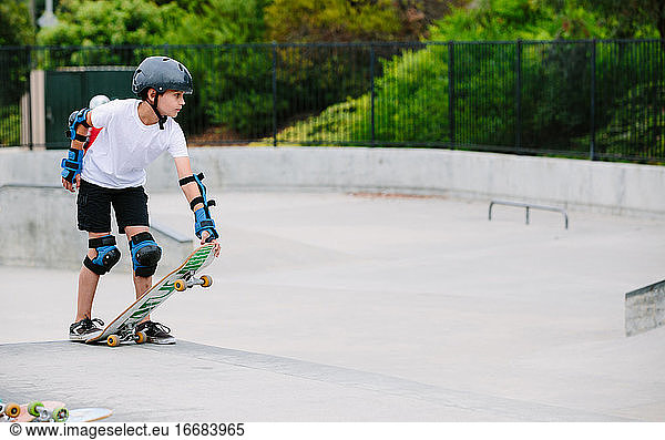 Boy at a skatepark prepares to go down the concrete canyon