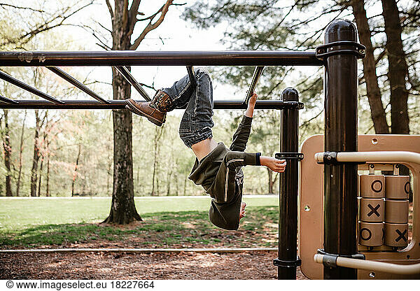 Boy at playground hanging on monkey bars