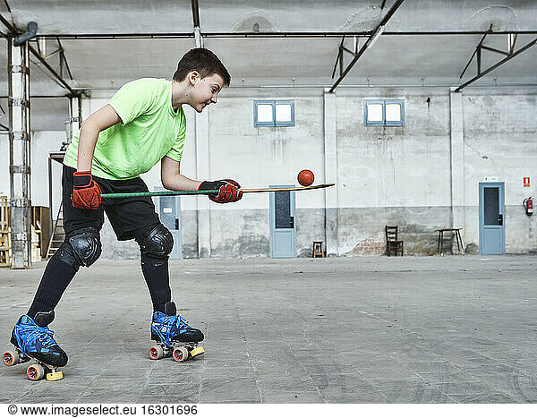 Boy balancing ball on hockey stick during training at court