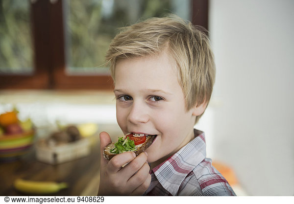 Boy biting off piece of bread and butter