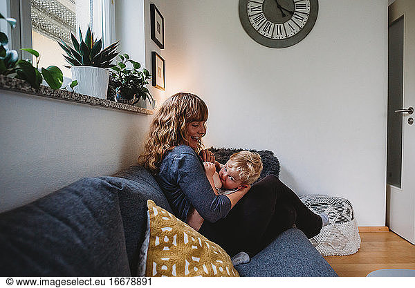 Boy breastfeeding at home with mom smiling in living room