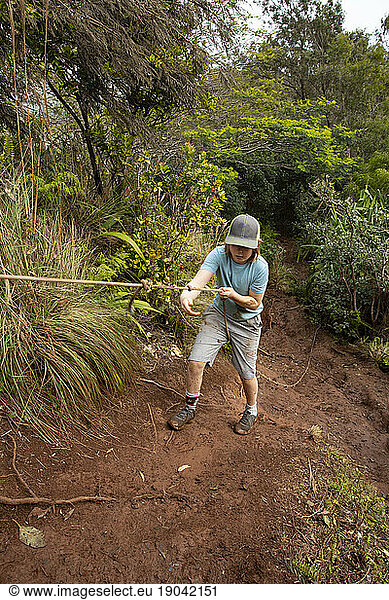 Boy climbing steep  slippery path with rope  Kauai