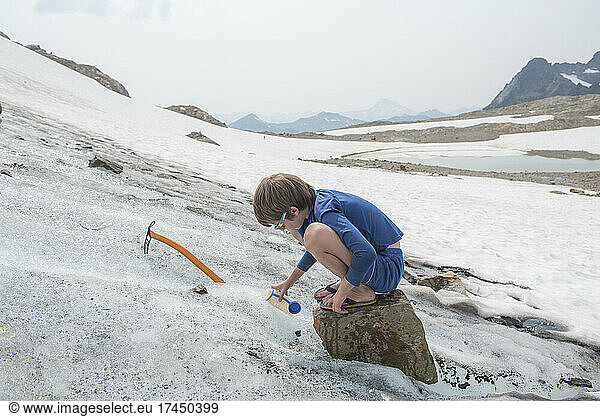 Boy collects water from a glacier near Glacier Peak  WA.