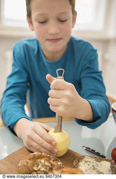 Boy coring apple in kitchen