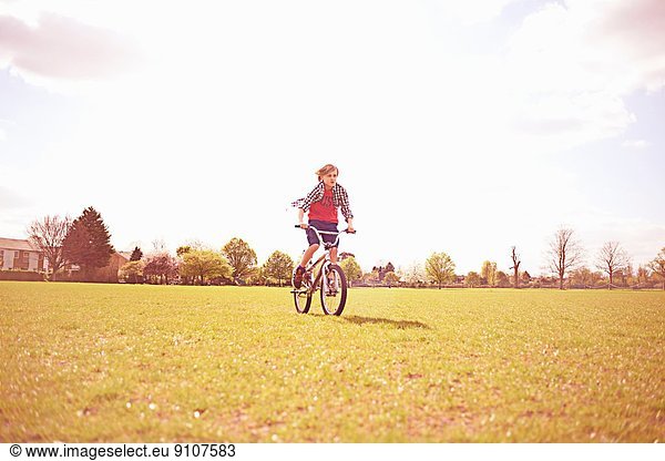 Boy cycling on playing field