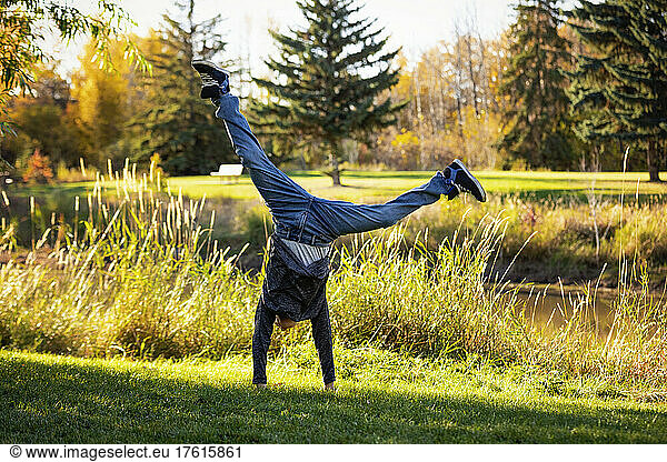 Boy doing a cartwheel in a park with autumn colours; St. Albert  Alberta  Canada