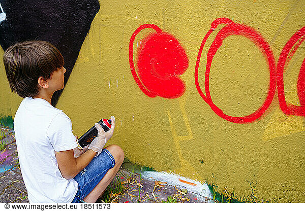 Boy drawing graffiti on the city wall