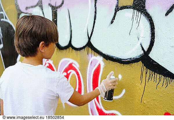 Boy drawing graffiti on the wall