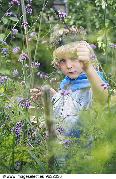 Boy dressed up and playing with plants in garden