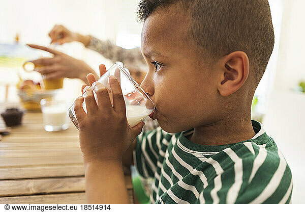 Boy drinking milk in glass at home