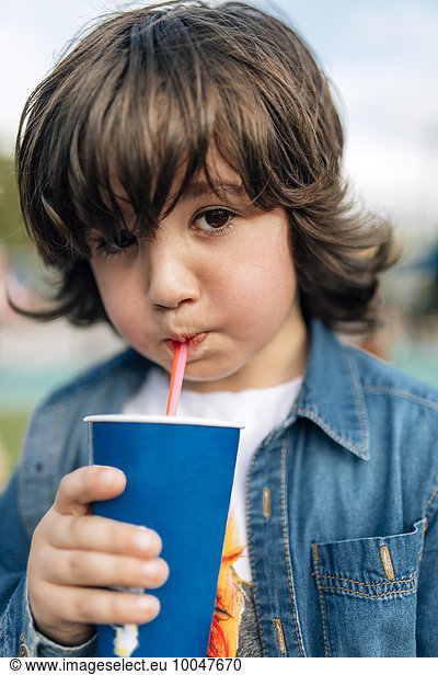 Boy drinking with straw from disposable cup
