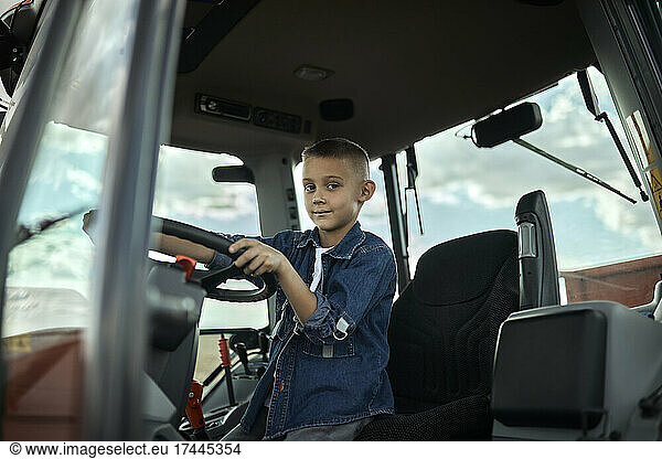 Boy driving tractor in agricultural field