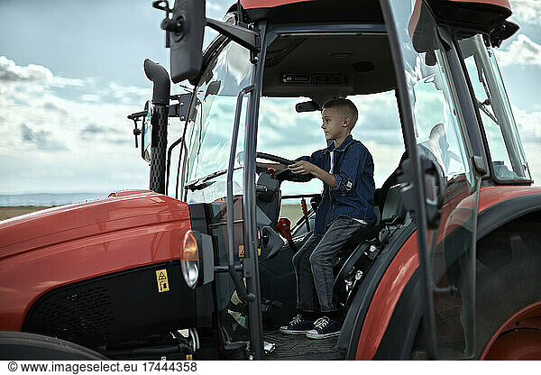 Boy driving tractor on farm