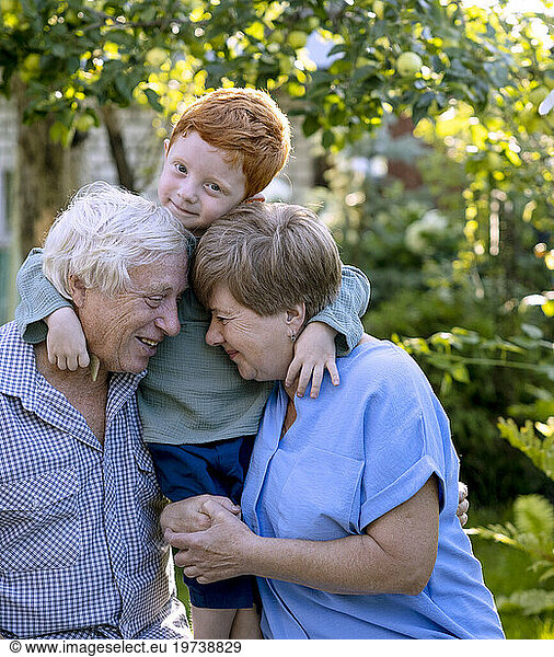 Boy embracing grandparents in garden