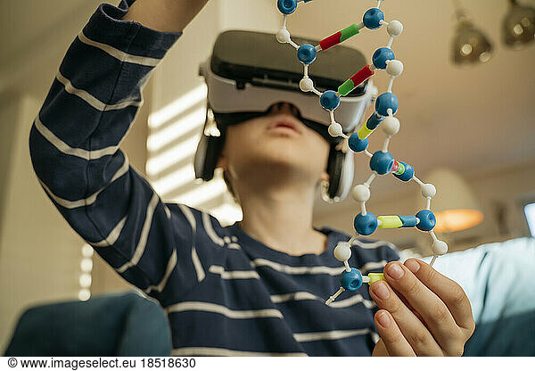 Boy examining DNA model through VR glasses at home