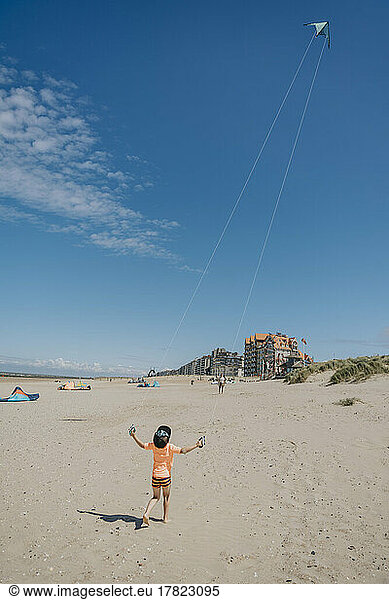 Boy flying kite on sunny day at beach