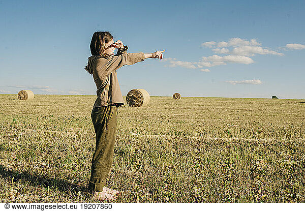Boy gesturing in field at sunny day