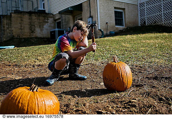 Boy gets ready to hit a pumpkin with a hammer