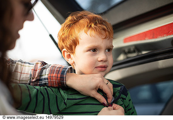 Boy getting fresh change of clothes at car boot