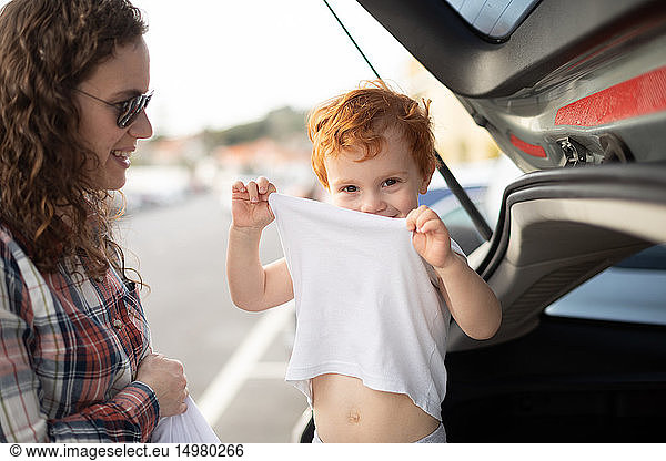 Boy getting fresh change of clothes at car boot