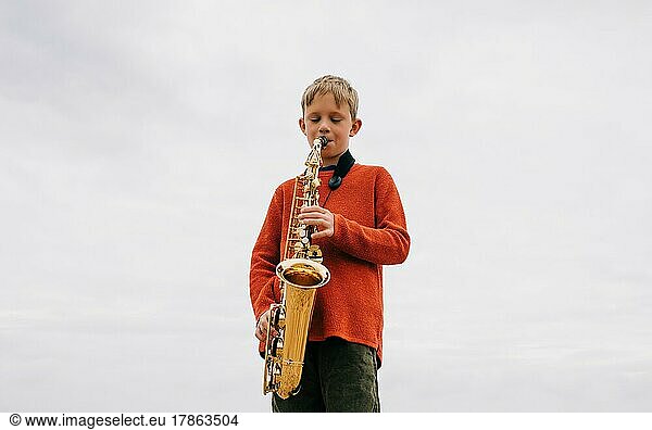boy happily playing the saxophone outdoors