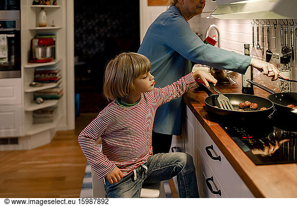 Boy helping grandmother in cooking food at home