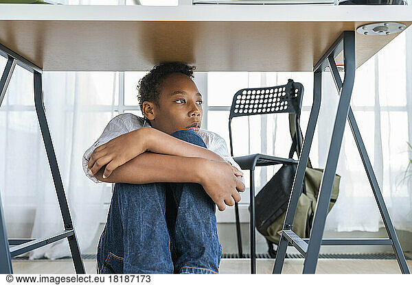 Boy hiding under table at home