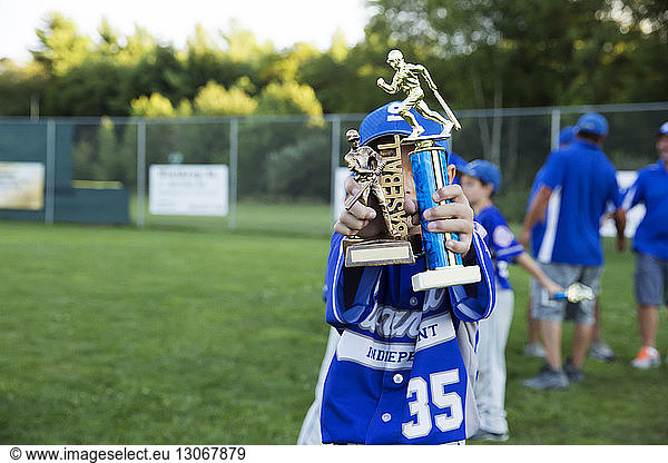 Boy holding baseball trophy on field