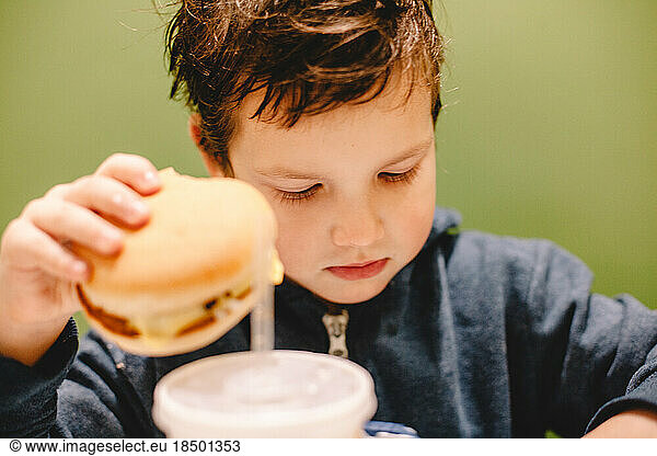Boy holding burger while sitting at restaurant