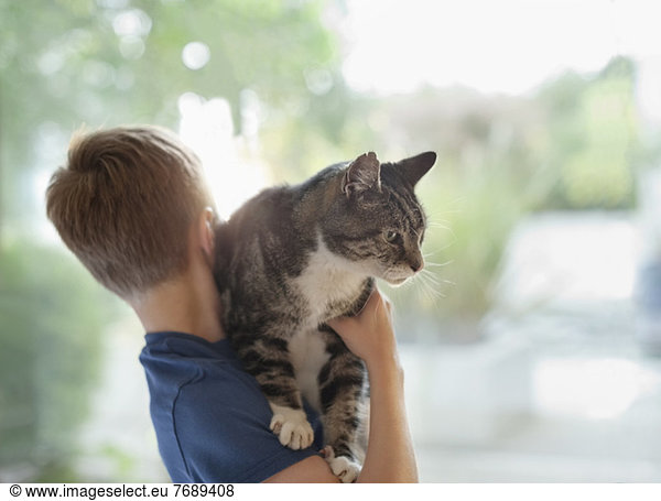 Boy holding cat indoors