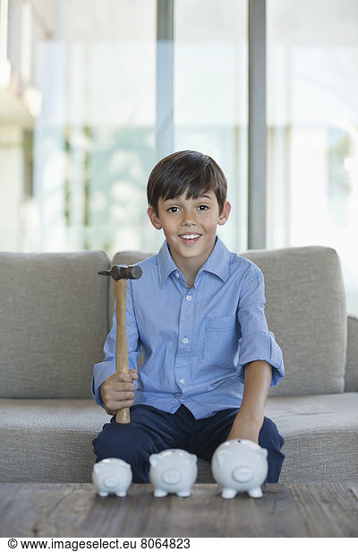 Boy holding hammer to smash piggy banks