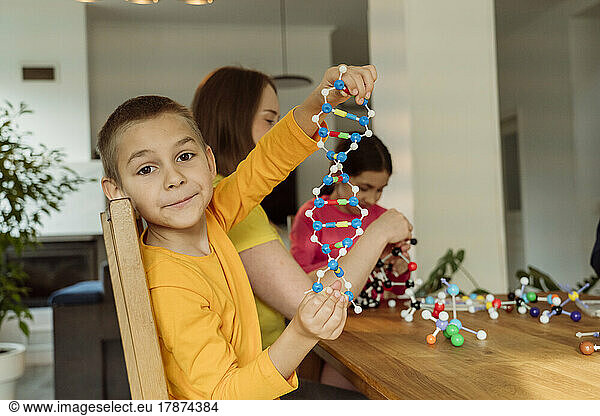 Boy holding helix model by mother at home