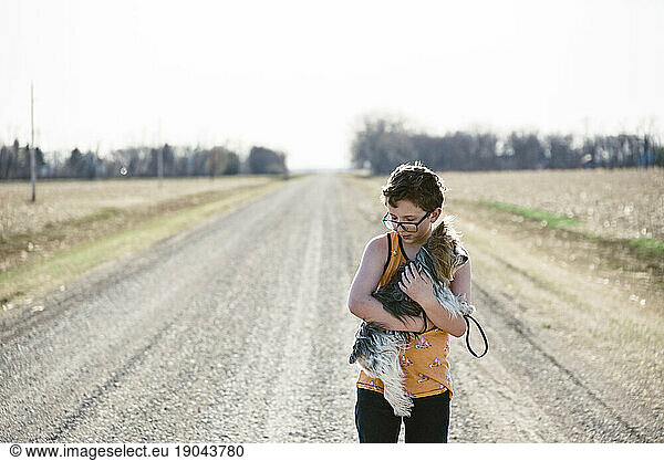 Boy holding his dog while exploring out on a dirt road.